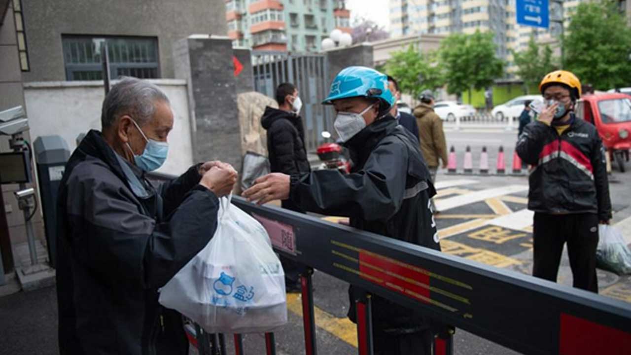 Beijing'in-Chaoyang-Bölgesi'ndeki-bir-topluluğun-girişinde-paketleri-teslim-alan-bir-bölge-sakini