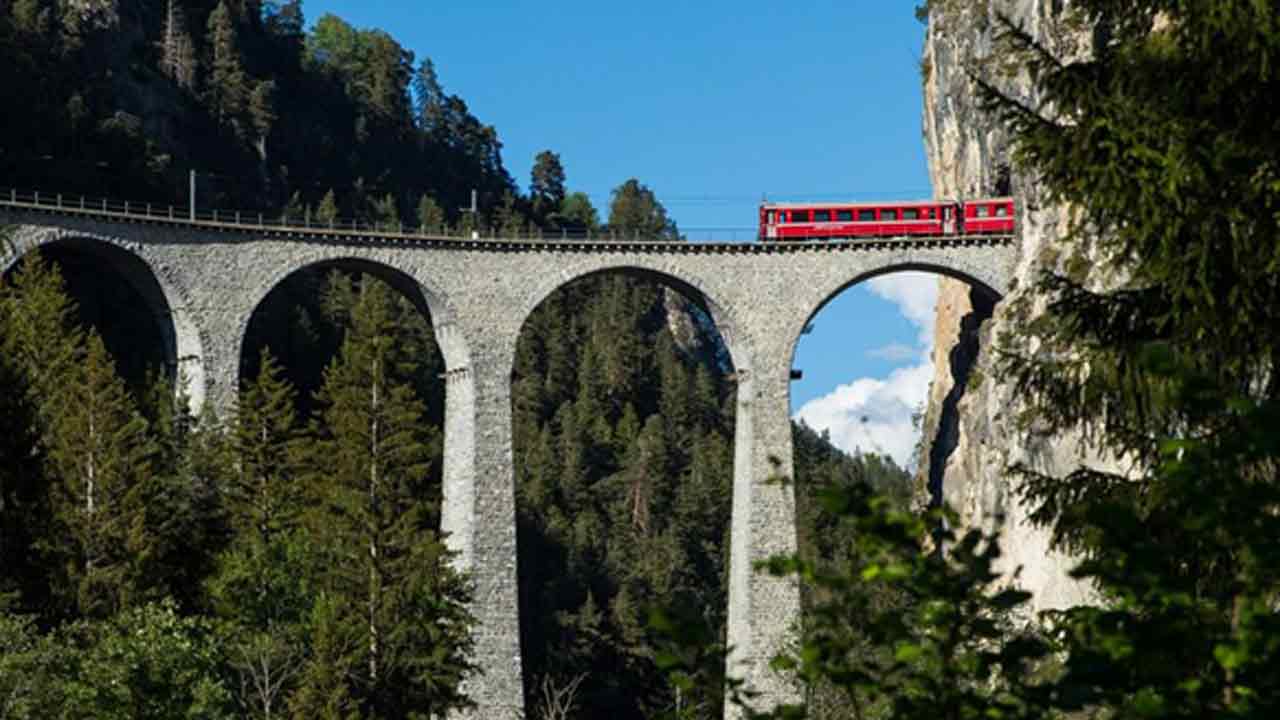 Bernina-hattında-uzanan-Rhaetian-Demiryolu'nda-eşsiz-manzarada-ilerleyen-bir-tren-görülüyor