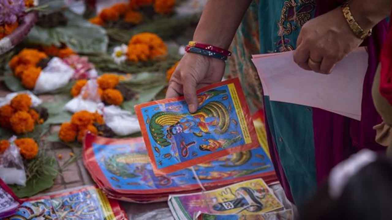 Lalitpur-kentinde-bir-kadın-Naga-Panchami-festivali-vesilesiyle-naga-(yılan)-posterleri-satın-alıyor